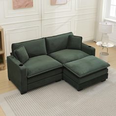 a green couch sitting on top of a rug in front of a white wall and floor