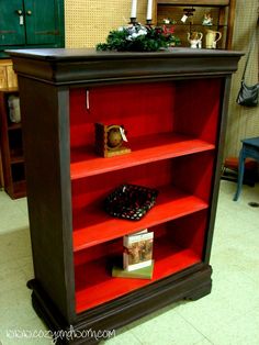 a red book shelf with some books on it and a basket in the bottom drawer