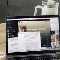 an open laptop computer sitting on top of a wooden table next to a white mug