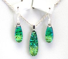 "Dichroic fused glass earring and pendant set. Handmade on Maui.  Emerald sparkle on jungle green glass.  The pendant measures  3/8\" wide and 15/16\" tall and comes with an 18\" sterling silver chain. The earrings are 5/8\" from below the ear wire. The ear wires are sterling silver.  Niobium is available upon request for those with metal allergies.  We mail in a white gift box with an Aloha card describing our work." Green Teardrop Glass Jewelry, Unique Green Drop Jewelry, Unique Green Drop-shape Jewelry, Green Glass Pendant Jewelry, Green Recycled Glass Pendant Jewelry, Green Teardrop Czech Glass Jewelry, Green Czech Glass Teardrop Jewelry, Earring And Pendant Set, Fusing Glas