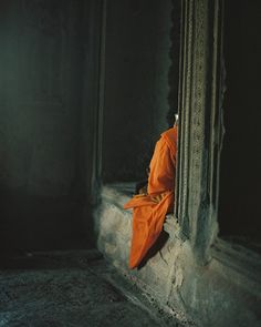 an orange cloth draped over the edge of a window sill in a dark room