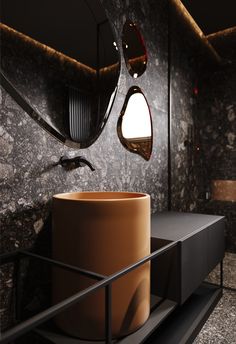 a modern bathroom with black marble walls and flooring, along with a round mirror on the wall