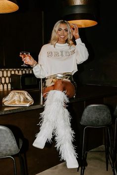 a woman sitting on top of a chair holding a wine glass in her right hand