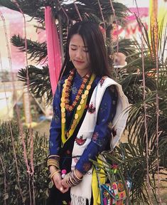 a woman standing in front of a tree wearing a colorful scarf and carrying a purse