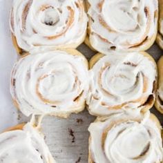 cinnamon rolls with white frosting in a baking pan