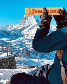 a person sitting in the snow holding up a sign that says toblerone on it