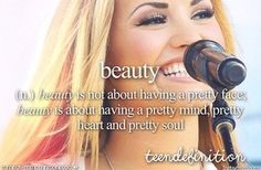 a woman singing into a microphone with a quote above her that reads beauty is not about having a pretty face