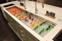 a kitchen sink filled with lots of different types of drinks on top of ice cubes