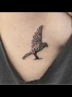 a woman's chest with a small tree tattoo on it