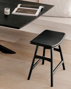 a black stool sitting next to a table with a laptop on it and a tablet