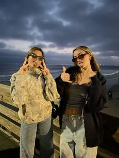 two women standing next to each other near the ocean