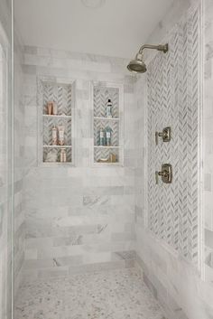 a walk in shower sitting next to a white tiled wall with shelves on the side