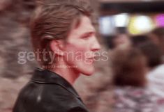 a blurry image of a man in a leather jacket looking off to the side