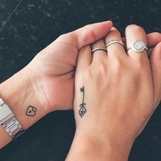 two people holding hands with tattoos on their fingers