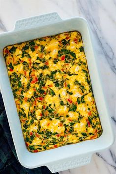 a casserole dish with spinach and cheese in it on a marble surface