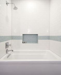 a white bath tub sitting inside of a bathroom next to a shower head and faucet