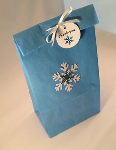 a blue paper bag with snowflakes on it and a thank you tag attached