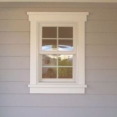 a white window sitting on the side of a gray house