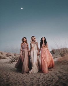 three women standing in the desert holding hands