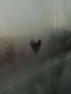 a heart shaped object sitting on top of a window covered in raindrops,