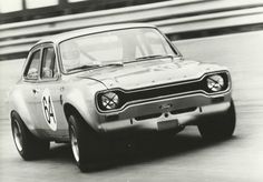 an old photo of a car driving on a track with numbers painted on the front