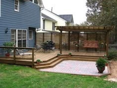 a backyard with a deck, patio and pergolated area in the back yard