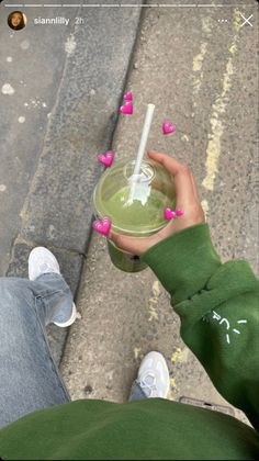 a person holding a drink in their hand on the sidewalk with hearts coming out of it