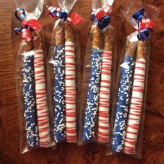 three patriotic candles wrapped in plastic and tied with red white and blue ribbon on wooden table