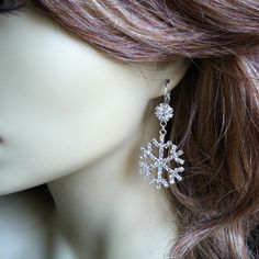 a close up view of a snowflake earrings on a mannequin head