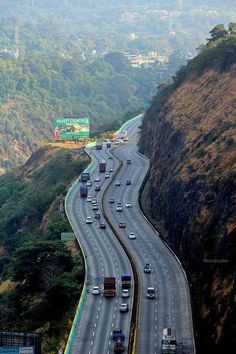 an aerial view of a highway with many cars on the road and mountains in the background