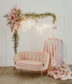 a pink couch and chair sitting in front of a neon sign that says better together