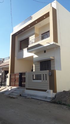 a white and brown building with balconies on the second floor, next to a fence