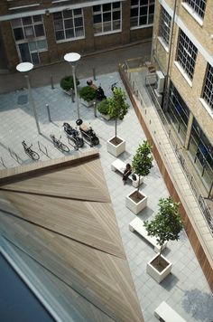 an aerial view of a courtyard with benches, trees and bicycles in planters on the ground