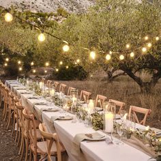 a long table is set up with candles and place settings for an outdoor dinner party