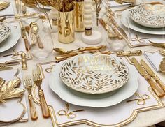 the table is set with gold and white plates, silverware, and napkins