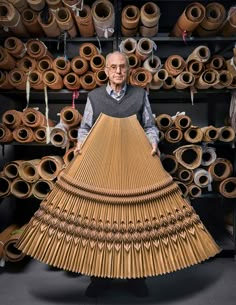 an older man standing in front of a large amount of rolls of paper and bamboo