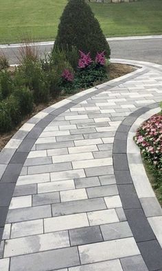 a paved walkway with flowers and bushes on either side