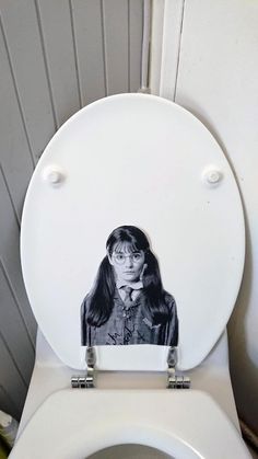 a white toilet with a black and white photo of a woman's face on the lid