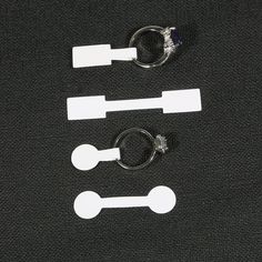 three pairs of scissors and two rings on a black surface with white tags attached to them