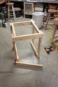 a wooden frame sitting on top of a floor in a room filled with furniture and tools