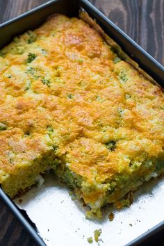 a casserole dish with broccoli and cheese in it on a wooden table