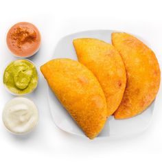 three pieces of fried food on a plate with dips and sauces around it