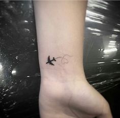 a small airplane tattoo on the left inner forearm and wrist is shown in black ink