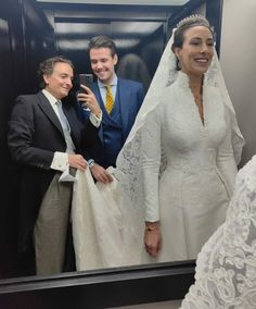 a man and woman taking a selfie in front of a mirror wearing wedding gowns