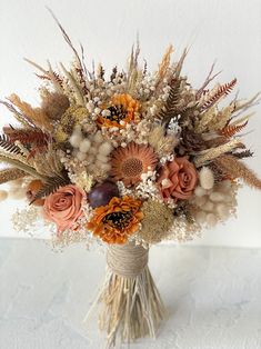 a vase filled with lots of different types of flowers on top of a white table