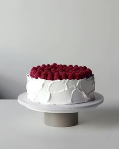 a cake with white frosting and raspberries on top