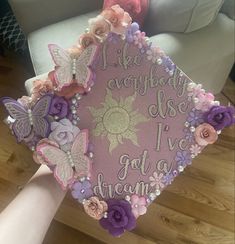 someone is holding up a graduation cap decorated with flowers and butterfly decorations that read, i like anybody else i've got to dream