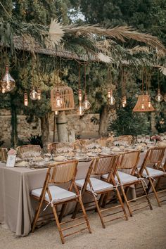 an outdoor dining area with wooden chairs and tables set up for a formal function, surrounded by greenery