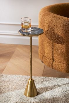 a glass of whiskey sitting on top of a table next to a chair and rug