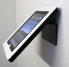 an ipad mounted to the side of a white wall with a black tablet on it